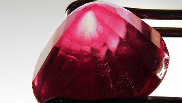 A portion of the near-colorless corundum seed is revealed in an area where the synthetic ruby overgrowth was cut away. A portion of the near-colorless corundum seed is revealed in an area where the synthetic ruby overgrowth was cut away.