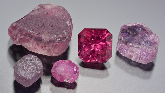 The 1.70 ct Montana ruby alongside rough corundum reference samples The 1.70 ct Montana ruby alongside rough corundum reference samples