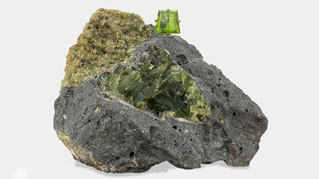Peridot nodule in host basalt, with a faceted peridot sitting atop. Peridot nodule in host basalt, with a faceted peridot sitting atop.