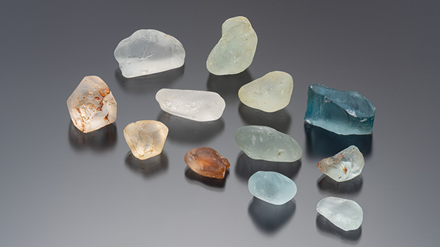 Figure 2. Rough topaz from Mason County analyzed in this study, showing the range of color of this material. The large blue specimen weighs 188 ct. Photo by Emily Lane; courtesy of Diane Eames. Figure 2. Rough topaz from Mason County analyzed in this study, showing the range of color of this material. The large blue specimen weighs 188 ct. Photo by Emily Lane; courtesy of Diane Eames.