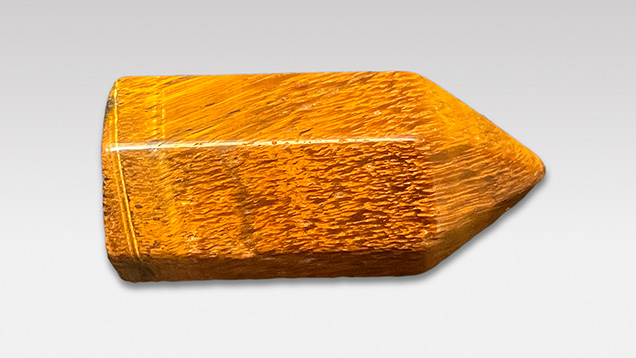 Figure 7. This polished specimen of tiger’s-eye (3.5 × 1.6 mm, 14.57 g) exhibits a golden yellow coloration similar to that of petrified tree fern. Photo by Ying Yan. Figure 7. This polished specimen of tiger’s-eye (3.5 × 1.6 mm, 14.57 g) exhibits a golden yellow coloration similar to that of petrified tree fern. Photo by Ying Yan.