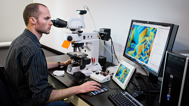 Figure 5. Nathan Renfro using the Nikon photomicroscope for observation and photography of inclusions and other micro-features at magnifications up to 1000×. Photo by Kevin Schumacher. Figure 5. Nathan Renfro using the Nikon photomicroscope for observation and photography of inclusions and other micro-features at magnifications up to 1000×. Photo by Kevin Schumacher.