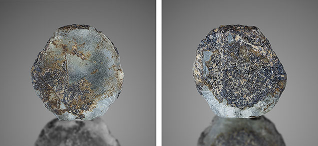Figure 16. This 5.23 ct, 13.7 mm French Bar sill sapphire (RK-FBS 041) still shows the rarely occurring triangular pattern on the basal plane, among significant resorption that occurred during the magmatic transport to the surface (left). The other side of the same crystal shows much adhering biotite (phlogopite), as well as other mineralization (right). Photos by Jeff Mason. Figure 16. This 5.23 ct, 13.7 mm French Bar sill sapphire (RK-FBS 041) still shows the rarely occurring triangular pattern on the basal plane, among significant resorption that occurred during the magmatic transport to the surface (left). The other side of the same crystal shows much adhering biotite (phlogopite), as well as other mineralization (right). Photos by Jeff Mason.