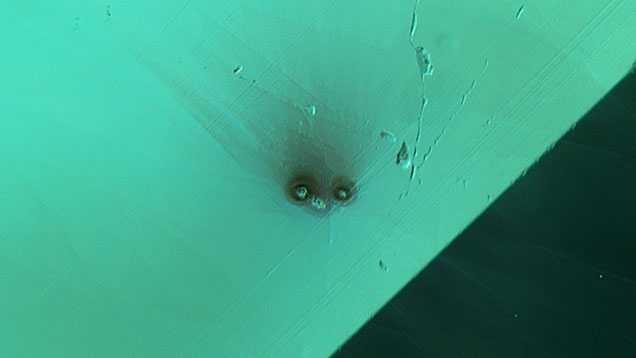 Figure 2. Top view of an altered etch tube in tourmaline resembling the face of a bird with a fuzzy tuft. Photomicrograph by Jamie Price; field of view 1.48 mm. Figure 2. Top view of an altered etch tube in tourmaline resembling the face of a bird with a fuzzy tuft. Photomicrograph by Jamie Price; field of view 1.48 mm.