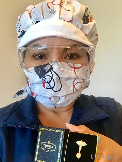A nurse in googles and a mask holds a box with the Defeating the Coronavirus pin in it.
