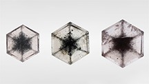 Three near-colorless transparent grossular garnet tablets with black inclusions arranged in snowflake-like patterns: 0.46, 0.68, and 1.00 ct, respectively. Photo by Shunsuke Nagai. Three near-colorless transparent grossular garnet tablets with black inclusions arranged in snowflake-like patterns: 0.46, 0.68, and 1.00 ct, respectively. Photo by Shunsuke Nagai.