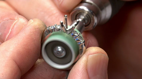 Close-up view of a jeweler using a rotary burnisher to prefinish the inside of a platinum ring Close-up view of a jeweler using a rotary burnisher to prefinish the inside of a platinum ring