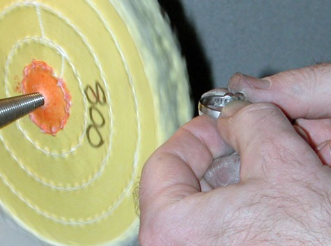 Jeweler polishing a platinum ring at a polishing machine. Jeweler polishing a platinum ring at a polishing machine.