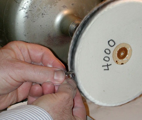Jeweler finishing the four-prong, platinum solitaire on the 4000 grit abrasive wheel Jeweler finishing the four-prong, platinum solitaire on the 4000 grit abrasive wheel