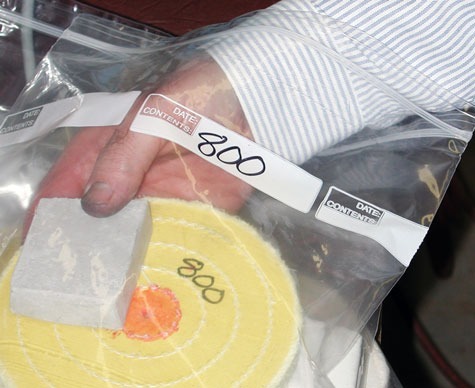 A jeweler placing a yellow platinum polishing wheel labeled “800” and compound into an individual storage bag also labeled “800” A jeweler placing a yellow platinum polishing wheel labeled “800” and compound into an individual storage bag also labeled “800”