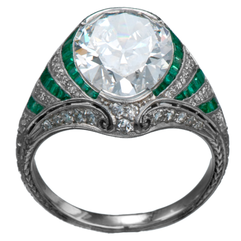 Perspective view of platinum ring with large diamond as the center stone. The shank is elaborate, with emerald baguettes alternating with channel-set round diamonds, millgrain, and other fine details. Perspective view of platinum ring with large diamond as the center stone. The shank is elaborate, with emerald baguettes alternating with channel-set round diamonds, millgrain, and other fine details.