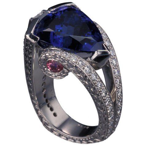 Perspective view of platinum ring with a large, trillion-cut tanzanite protected by a partial bezel as the center stone. The split shank is detailed with small gemstones, fine engraving, and millgrain. Perspective view of platinum ring with a large, trillion-cut tanzanite protected by a partial bezel as the center stone. The split shank is detailed with small gemstones, fine engraving, and millgrain.