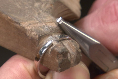 Close-up view showing a platinum band with a piece removed from the ring shank in preparation for sizing it down