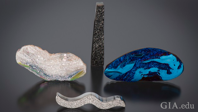 Organically shaped pieced of agate drusy with a variety of coatings. One with a silicone dioxide coating, one with a black titanium coating, one with a blue titanium coating and one with a platinum coating.
