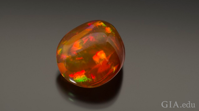 A polished gem with orange and green flashes of color. A polished gem with orange and green flashes of color.