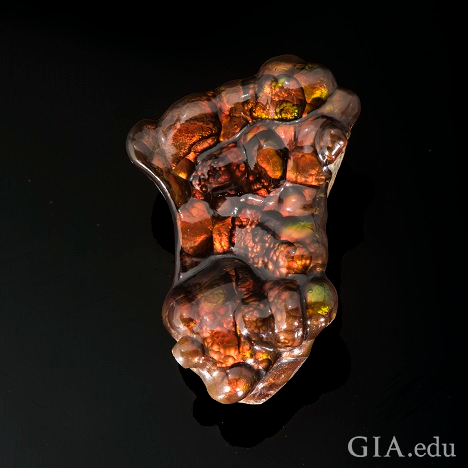 An irregular-shaped stone with orange, brown and green coloring. An irregular-shaped stone with orange, brown and green coloring.