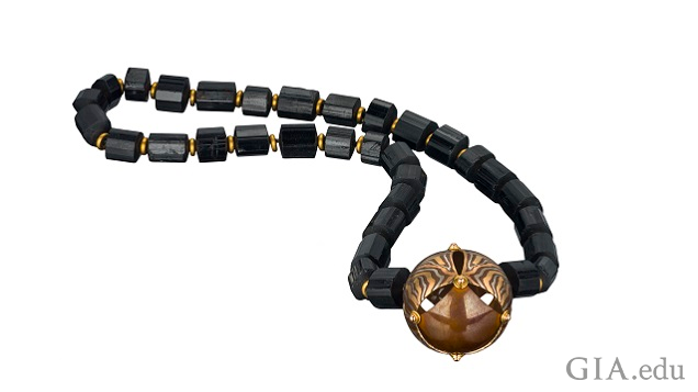 A mokume gane bead on a black gemstone necklace.