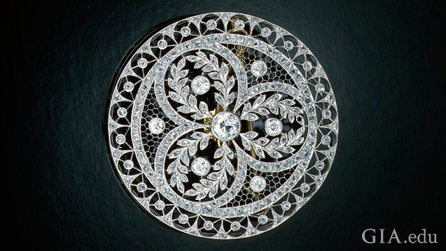 Circular pin with elaborate piercings and diamond embellishments.