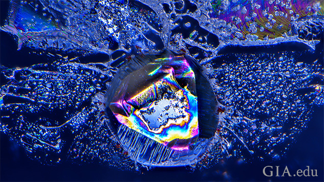 A negative crystal filled with carbonate and analcime minerals shows colorful thin-film interference in this untreated sapphire from Yogo Gulch, Montana. Field of view 1.28 mm.