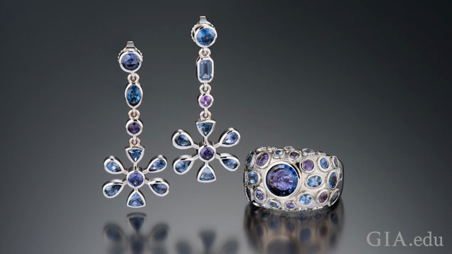 Earrings are flower-shaped and drop from a line of four blue and purple sapphires; the ring is domed-shaped with bezel-set blue and purple sapphires with a large blue center stone.