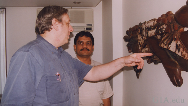 Two men look at a wall hanging. Two men look at a wall hanging.