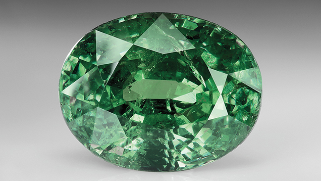 Up-close view of a faceted green gem. Up-close view of a faceted green gem.