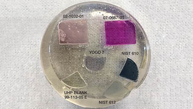 Figure 1. One of GIA’s new LA-ICP-MS corundum calibration standards sets (set number 1); the epoxy disk containing the set is 1.5 inches in diameter. NIST SRM 610 and 612 glass standards are included to account for trace and non-trace elements, such as those found in inclusions, that were not incorporated into the synthetic sapphire crystals grown for standards. Photo by Jennifer Stone-Sundberg. Figure 1. One of GIA’s new LA-ICP-MS corundum calibration standards sets (set number 1); the epoxy disk containing the set is 1.5 inches in diameter. NIST SRM 610 and 612 glass standards are included to account for trace and non-trace elements, such as those found in inclusions, that were not incorporated into the synthetic sapphire crystals grown for standards. Photo by Jennifer Stone-Sundberg.